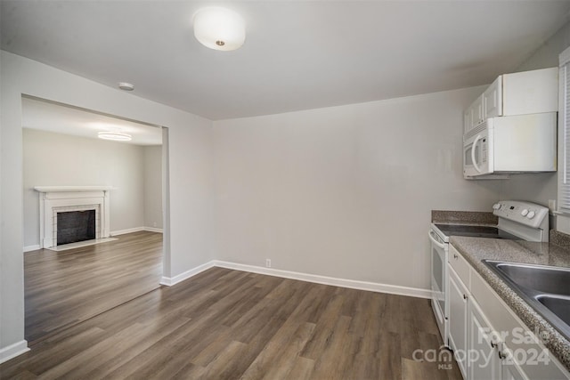 kitchen featuring white appliances, white cabinets, sink, a brick fireplace, and dark hardwood / wood-style floors