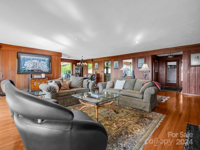 living room with hardwood / wood-style flooring, an inviting chandelier, and wooden walls