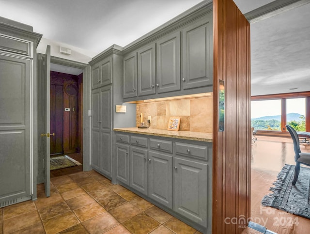 kitchen with a mountain view, decorative backsplash, gray cabinets, ornamental molding, and dark tile patterned floors