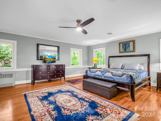 bedroom featuring radiator, ceiling fan, multiple windows, and light wood-type flooring