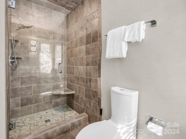 bathroom featuring toilet and a shower with shower door