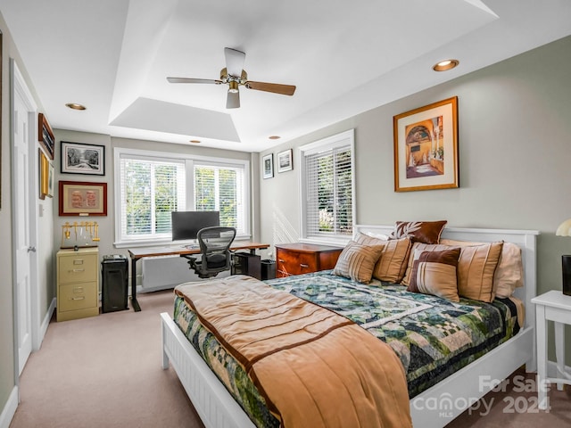 bedroom with light carpet, a tray ceiling, and ceiling fan