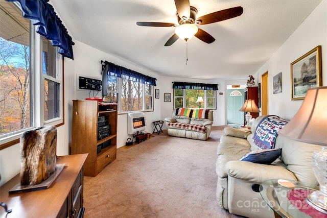 living room with heating unit, ceiling fan, and light colored carpet