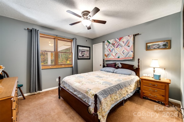 bedroom with ceiling fan, light colored carpet, and a textured ceiling