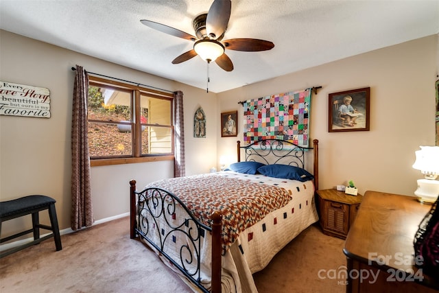 carpeted bedroom featuring ceiling fan and a textured ceiling