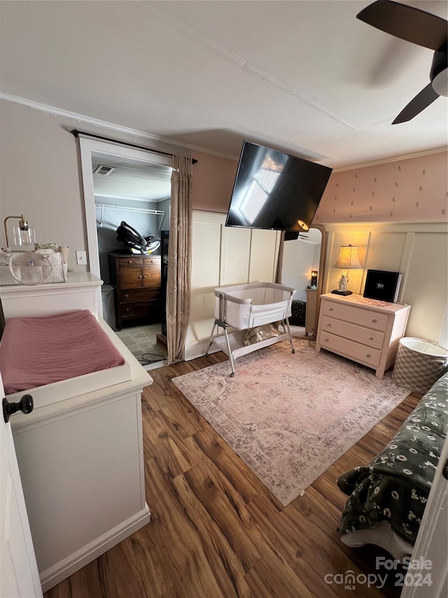 bedroom with crown molding, ceiling fan, and dark wood-type flooring