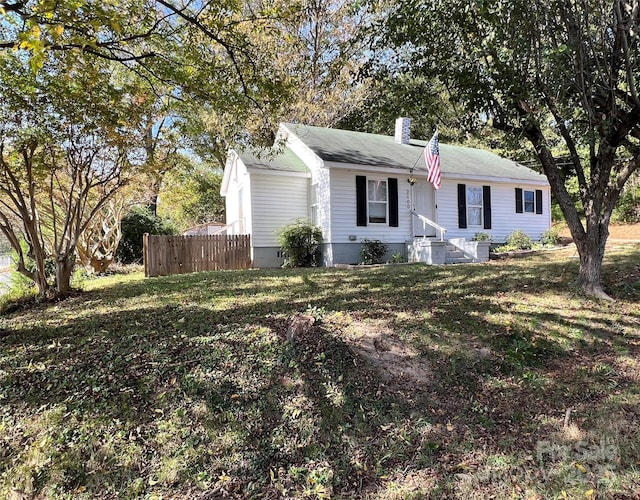 ranch-style home with a chimney, a front yard, and fence