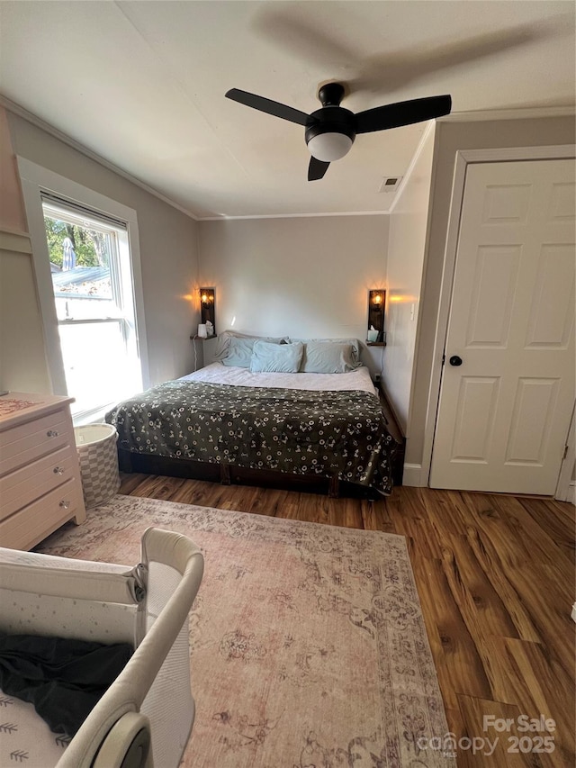 bedroom with dark wood-style floors, a ceiling fan, visible vents, and crown molding