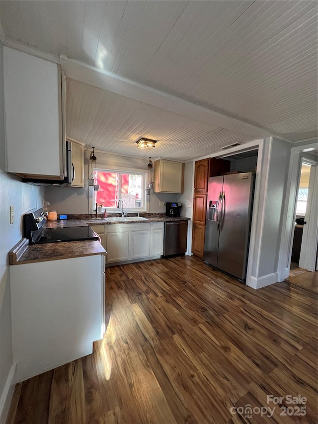 kitchen featuring dark countertops, a sink, stainless steel appliances, and dark wood-type flooring