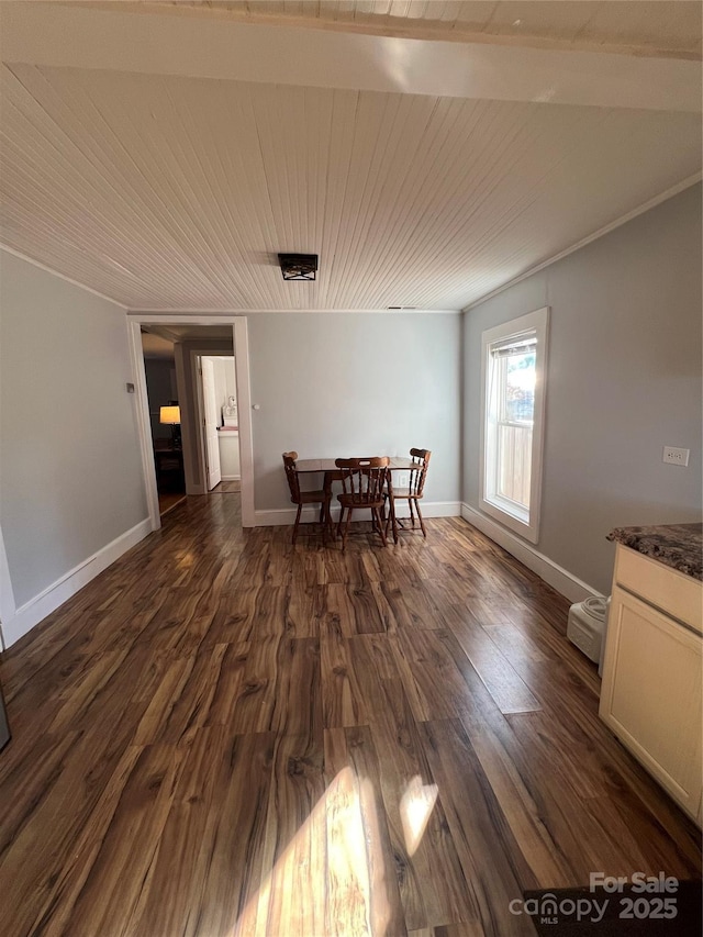 dining room with dark wood-type flooring, wood ceiling, ornamental molding, and baseboards