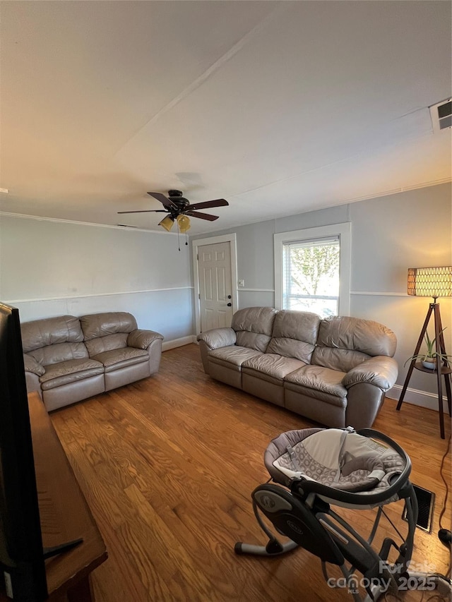 living room with a ceiling fan, visible vents, baseboards, and wood finished floors