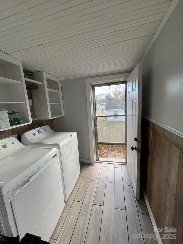 washroom with laundry area, wooden walls, a wainscoted wall, washing machine and clothes dryer, and wood finish floors