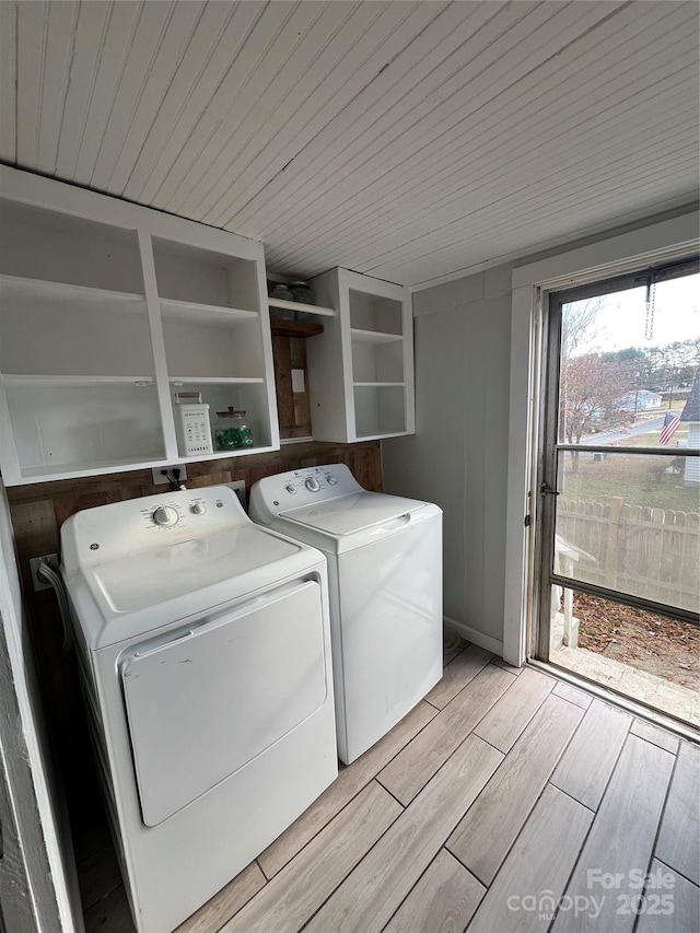 washroom featuring light wood-style floors, wood ceiling, laundry area, and washing machine and clothes dryer