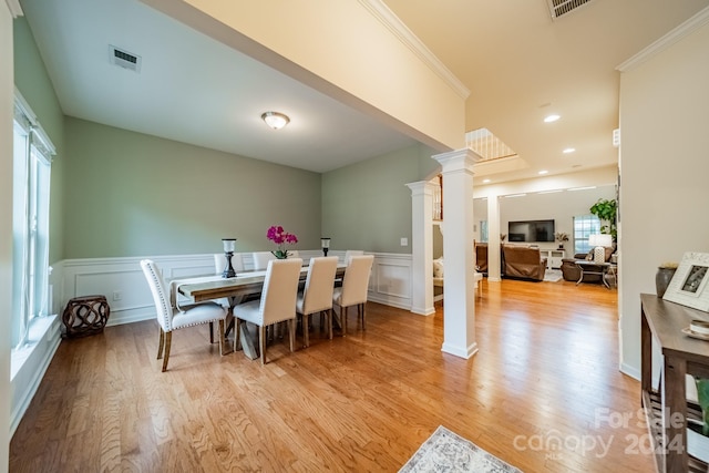 dining room featuring light hardwood / wood-style flooring, ornamental molding, and ornate columns