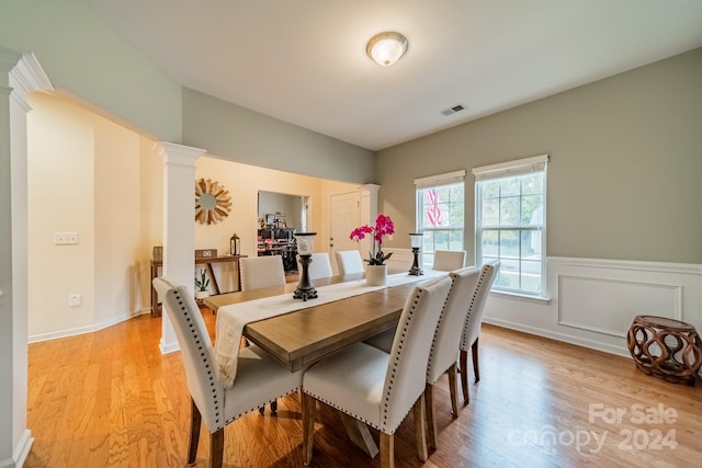 dining space featuring light wood-type flooring and ornate columns