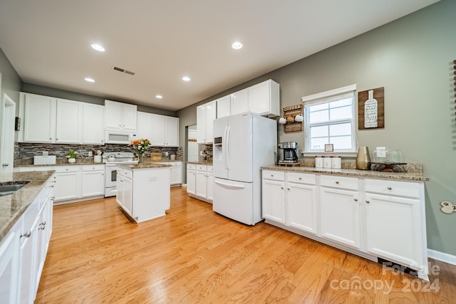 kitchen with white cabinetry, light stone counters, white appliances, a kitchen island, and light wood-type flooring