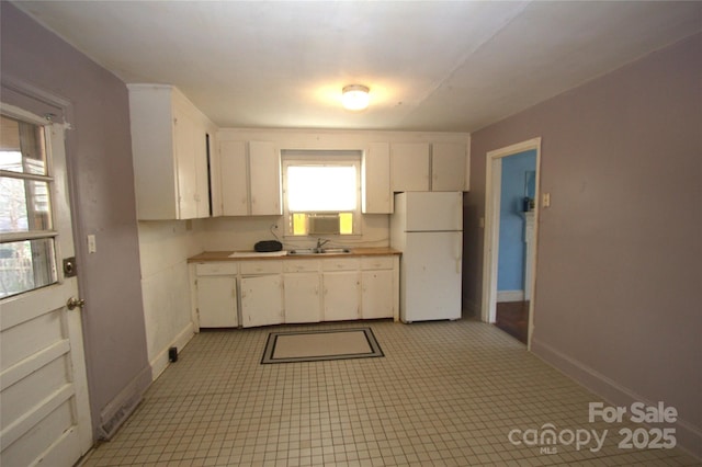 kitchen featuring white cabinets, white refrigerator, sink, and cooling unit