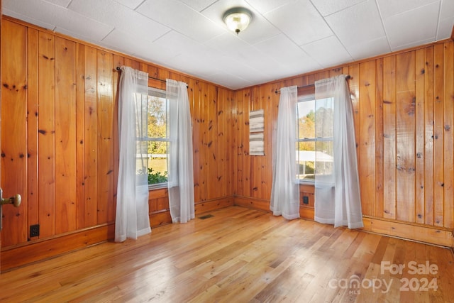 spare room featuring light hardwood / wood-style flooring, a wealth of natural light, and wooden walls