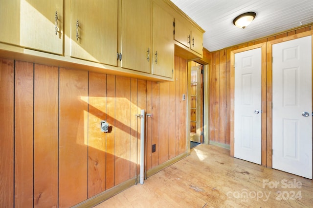 clothes washing area with wood walls and light wood-type flooring