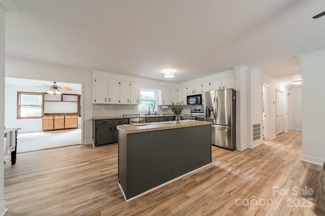 2109 Rock Springs Cir, Denver, NC 28037 - kitchen featuring appliances with stainless steel finishes, a ceiling fan, white cabinetry, light wood-type flooring, and decorative backsplash