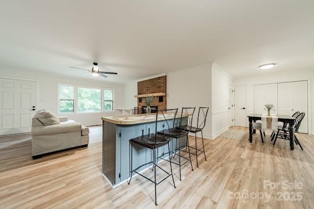 2109 Rock Springs Cir, Denver, NC 28037 - kitchen with tile counters, a breakfast bar, light wood-style floors, ceiling fan, and crown molding
