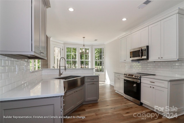 kitchen featuring dark wood-type flooring, sink, hanging light fixtures, tasteful backsplash, and stainless steel appliances