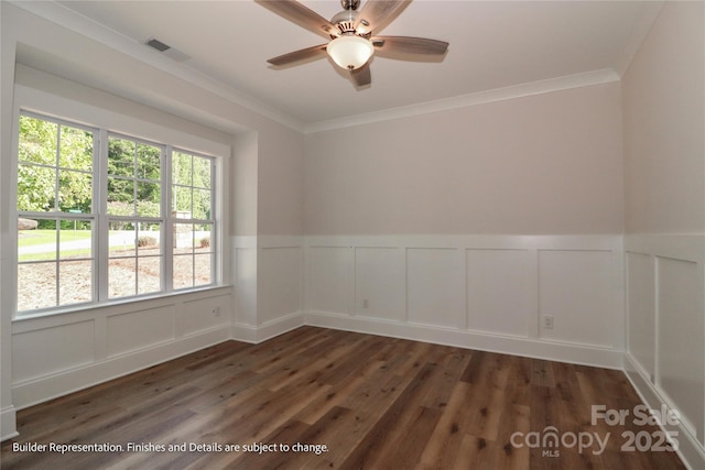 empty room featuring crown molding, a decorative wall, a ceiling fan, and wood finished floors