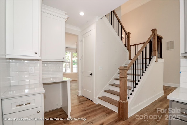stairway with recessed lighting, wood finished floors, visible vents, and baseboards