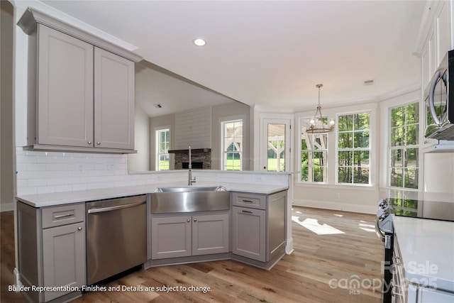 kitchen featuring light wood-type flooring, appliances with stainless steel finishes, a notable chandelier, and gray cabinetry