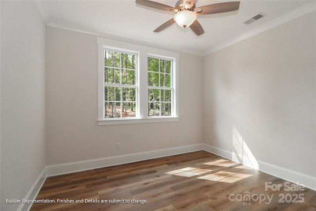 spare room featuring baseboards, wood finished floors, visible vents, and crown molding