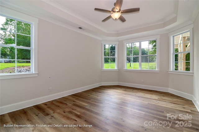 spare room featuring a raised ceiling, plenty of natural light, and visible vents