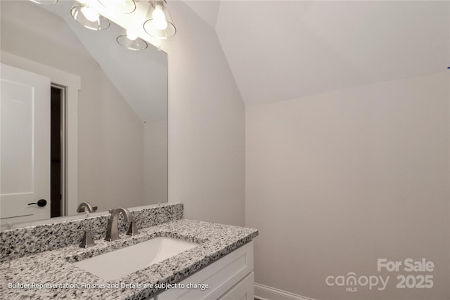 bathroom with lofted ceiling, vanity, and baseboards
