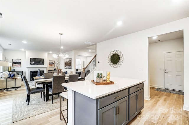 kitchen featuring pendant lighting, a breakfast bar, a center island, gray cabinets, and light wood-type flooring