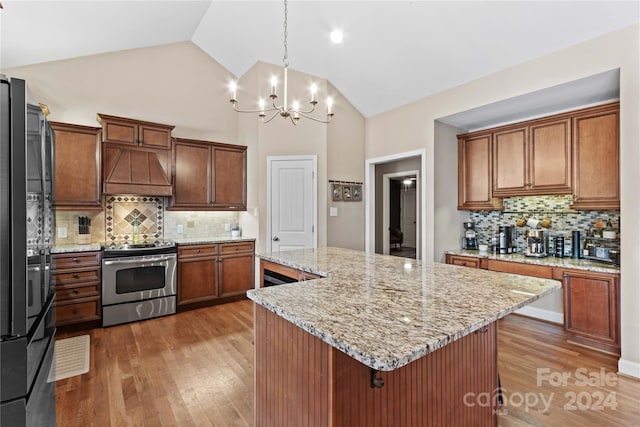 169 Rimmer Farm Rd, Troutman, NC 28166 - kitchen with stainless steel range with electric stovetop, wall chimney exhaust hood, a center island, a chandelier, and tasteful backsplash