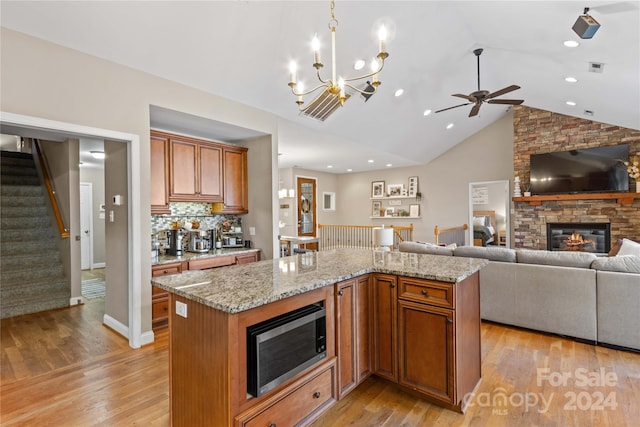 169 Rimmer Farm Rd, Troutman, NC 28166 - kitchen featuring stainless steel microwave, open floor plan, a fireplace, ceiling fan, and light wood-style flooring