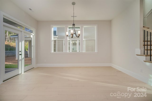 unfurnished dining area with french doors and an inviting chandelier