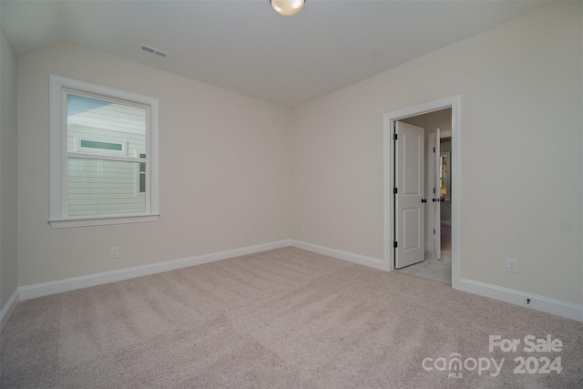 carpeted empty room with vaulted ceiling