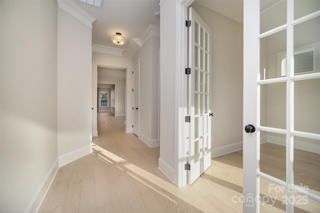 hall with light wood-style floors, french doors, ornamental molding, and baseboards