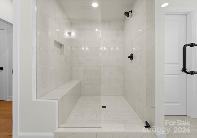 bathroom with tiled shower and hardwood / wood-style floors