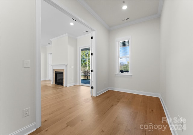 unfurnished living room featuring light hardwood / wood-style flooring and crown molding