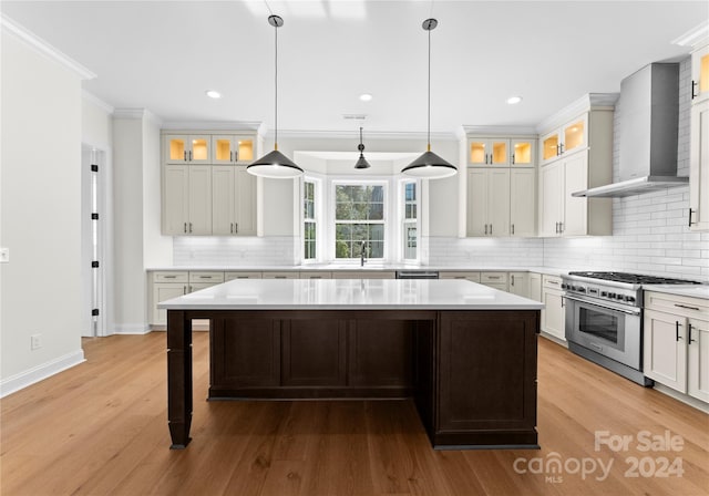 kitchen with a center island, wood-type flooring, wall chimney range hood, and stainless steel stove