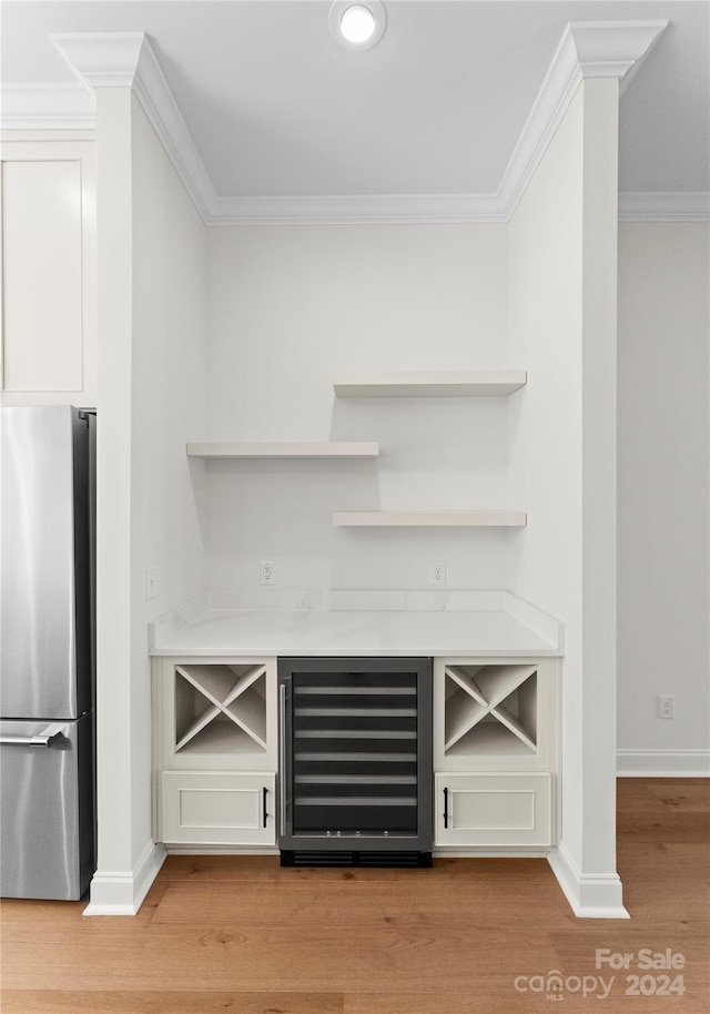 bar with white cabinets, wine cooler, stainless steel fridge, ornamental molding, and light hardwood / wood-style floors