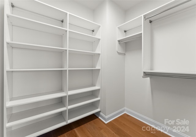 spacious closet with dark hardwood / wood-style flooring