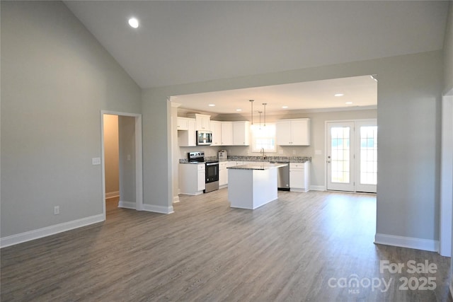 kitchen featuring a center island, light hardwood / wood-style floors, appliances with stainless steel finishes, white cabinets, and decorative light fixtures