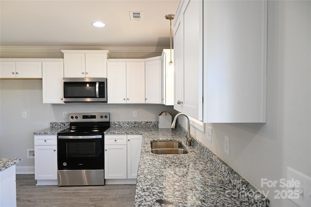 kitchen with appliances with stainless steel finishes, white cabinetry, sink, ornamental molding, and light stone counters