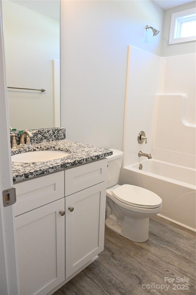 full bathroom with tub / shower combination, hardwood / wood-style floors, toilet, and vanity