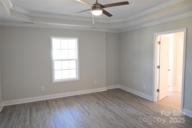 spare room with ceiling fan, wood-type flooring, a tray ceiling, and crown molding