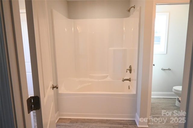 bathroom featuring  shower combination, toilet, and hardwood / wood-style floors