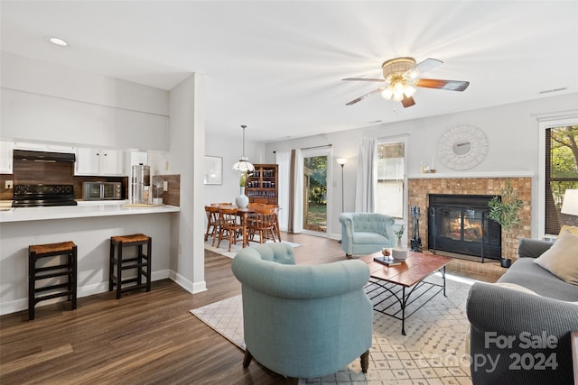 living room with hardwood / wood-style flooring, ceiling fan, and a tiled fireplace