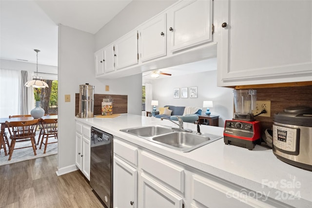 kitchen with sink, hanging light fixtures, black dishwasher, white cabinets, and light wood-type flooring